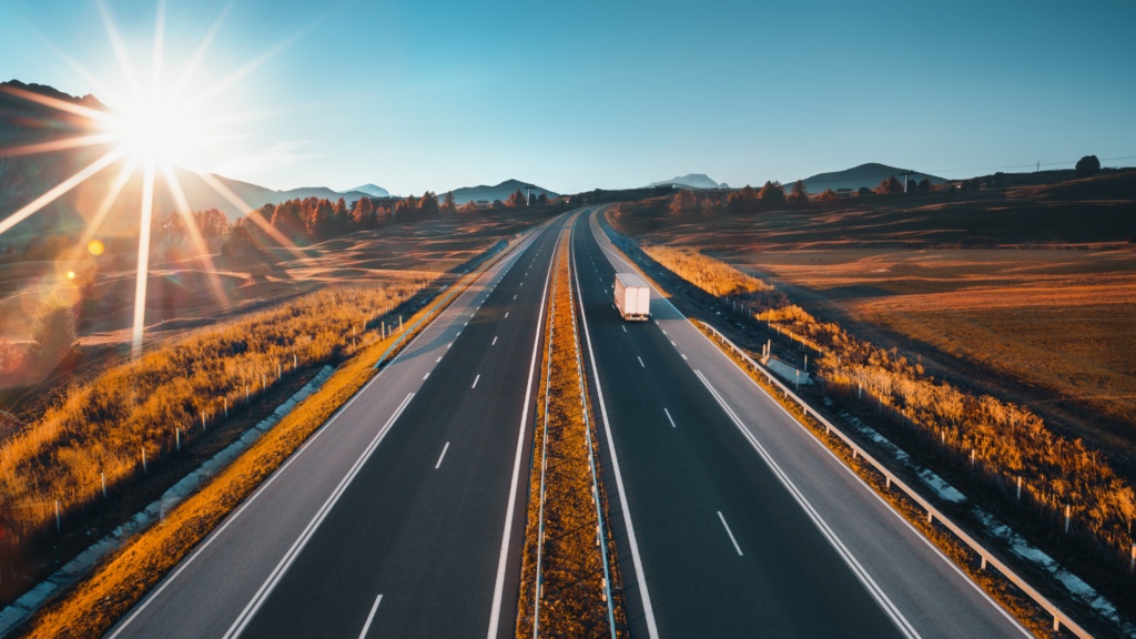 Freight truck traveling on an open highway at sunrise.